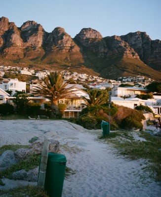 Twelve Apostles mountain range glowing at golden hour above the houses of Bakoven Beach