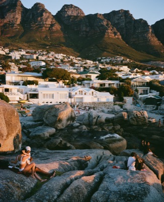 Couples relaxing on the granite boulders below the Twelve Apostles at sunset