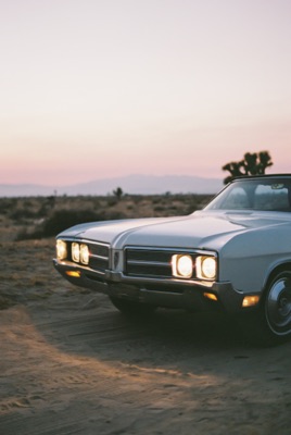 Vintage Buick parked at twilight beside a Joshua tree as the desert sky fades to pink