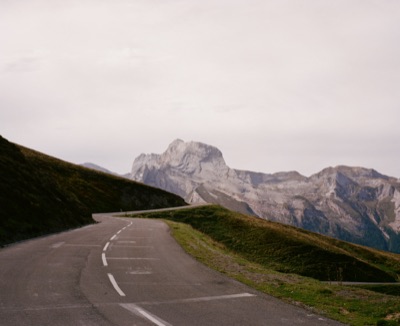 Empty mountain pass road curving toward the jagged peaks of the Pyrenees