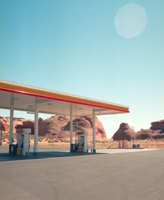 Empty desert gas station canopy framed against towering red sandstone formations
