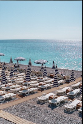 Rows of blue-and-white striped umbrellas and loungers stretching toward the Mediterranean