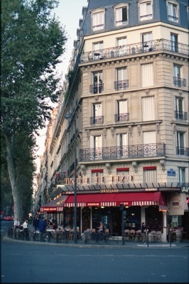 Paris brasserie awnings and Haussmannian façade glowing in early-evening light