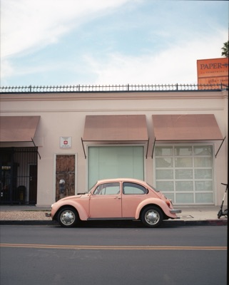 Pink Volkswagen Beetle parked outside a stationery shop on a sunlit LA side street