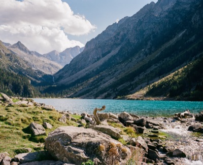 Boulders and a rocky outflow tumbling from the turquoise water of an alpine lake